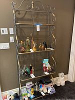 Full front view showing four glass shelves, metal frame with scrollwork and gold-tone accents