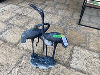 Front view showing two storks facing left and right on textured stone-like base