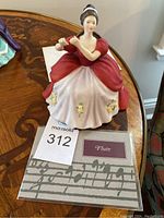 Front view of porcelain figurine of a woman in a red bodice and white skirt playing a flute.