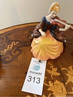 Front view of figurine on wood table with auction lot card.