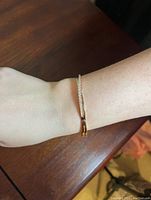 Bracelet worn on wrist showing its delicate size and rose gold colour with embedded clear crystals.