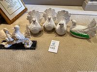 Five white dove figurines arranged on carpeted floor near a framed certificate.