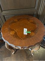 Front view of the round tabletop showing marquetry inlay and scalloped edge