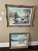 Two framed paintings leaning against wall
