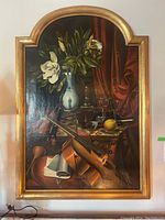 Full view of painting in gilt wooden arched frame showing violin, vase of flowers and draped cloth