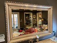 Front view of large rectangular mirror mounted on wall reflecting living room
