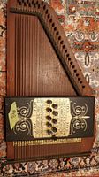 Top view of autoharp showing strings, wooden body, and ornate black panel with buttons and key instructions.