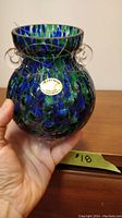 Front view of the blue, green, and clear bubble accented glass vase with hanging wire, showing seller's hand holding it