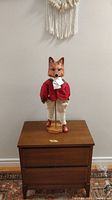 Full front view of dapper fox figurine standing on wooden chest, showing full height and pose