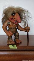 Full frontal view of the Nyform troll figurine showing body, face, hair, and stick