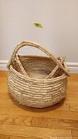 Front angled photo of vintage woven garden harvest basket showing top handles and base.