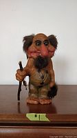 Front view of large vintage Norwegian Nyform troll figurine, showing detailed facial features, wooden body, holding walking stick with keys and tail in other hand.