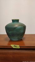 Front view of vintage turquoise glazed Salem-stamped earthenware vase on wooden surface