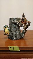 Front and side view of vintage ceramic vase with owl on one side and fawn climbing the handle side, showing textured bark and colors.