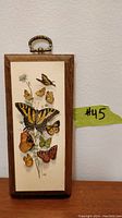 Full front view of the framed 3D butterfly paper art with butterflies arranged vertically and a decorative metal hanger on top