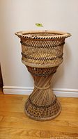 Front angle view of vintage wicker plant stand showing overall design and shape.