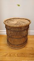 Side view of vintage wicker cylindrical side table showing woven texture and pattern on hardwood floor.