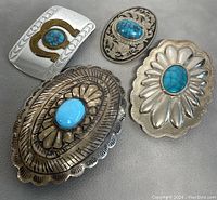 All four vintage belt buckles displayed on a neutral surface, showing front designs and turquoise stones.