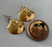Photo of the earrings and brooch side by side on a grey background.