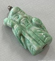 Angled side view of green jade wise man pendant showing carving details and metal loop attachment