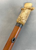 Close-up of cane handle showing detailed texture of deer antler and metal collar attachment to wooden shaft.