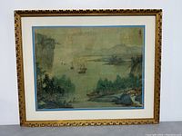 Full view of the framed Asian landscape art print featuring boats, water, trees and cliffs.