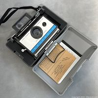 Polaroid 210 Land Camera in original gray plastic carrying case with user guide inside.