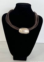 Front view on black display bust showing multi-strand leather cords and central silver bead