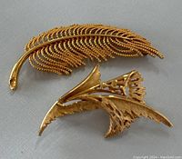 Back of the gold tone feather brooch showing clasp and signature area.