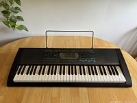 Full front view of Casio CTK-2100 keyboard piano on a wooden table.