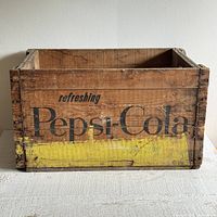 Front view of old wooden Pepsi-Cola crate featuring 'refreshing Pepsi-Cola' in faded black paint on wood with yellow paint base, showing age marks.