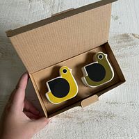 Pair of ceramic bird-shaped salt and pepper shakers inside original box, showing yellow and olive green colors with black wings.