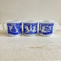 Three vintage Federal Glass mugs side-by-side showing full Blue Willow pattern in blue on white milk glass.