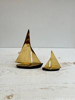 Pair of brass sailboat figurines, large and small, with brass sails and black bases, front view.