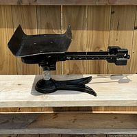 Side view of the black metal postal scale showing the curved balance pan, C.P.O. markings, and Canada Post label on the base.