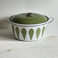 Front view of the white enamel Dutch oven with green lotus leaf pattern and green lid with metal knob, showing overall condition.