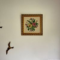 Full view of the embroidery art piece hanging on a wall with additional decorative birds nearby.