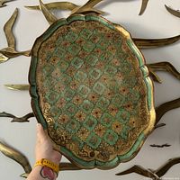 Full view of scalloped decorative tray held in hand showing overall shape and design.