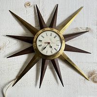 Full view of starburst clock mounted on wall showing alternating brass and wooden rays