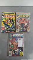 Three comic books laid flat: two Inhumans issues and one Micronauts issue, all in plastic protective sleeves.