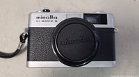 Front view of Minolta Hi-Matic G camera showing lens with cap and leatherette body covering