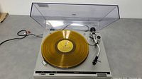 Full view of Technics SL-B2 turntable with clear dust cover and yellow translucent vinyl record on platter.