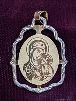 Close-up photo of the 10K gold pendant showing the Virgin Mary and child engraving and decorative gold frame on dark background.
