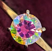 Close-up of round rainbow moissanite showing multicolored facets in six-prong setting