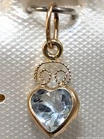 Close-up image of the heart-shaped blue topaz pendant set in gold showing the twisted wire decorative elements.