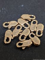 Close-up image of 14 gold fill lobster clasps placed on a black surface, showcasing the clasp shape and finish.