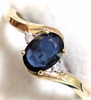 Front angle close-up showing oval blue sapphire and flanking diamonds