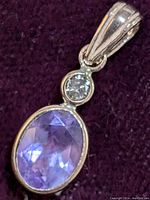 Pendant front close-up showing oval faceted purple amethyst and round diamond set in yellow gold