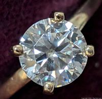 Top-down macro view of round brilliant moissanite in four-prong setting on gold band
