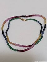 Full view of multi-colored faceted gemstone beaded necklace showcasing color range and clasp